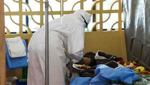 Медик в защитен костюм се грижи за пациент с ебола