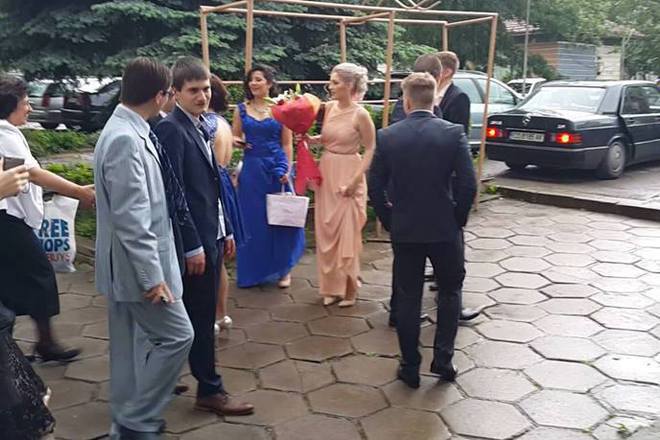 Abiturientat kristiyan v svetlosiniya kostyum i sauchenitsite mu se sabirat predi bala